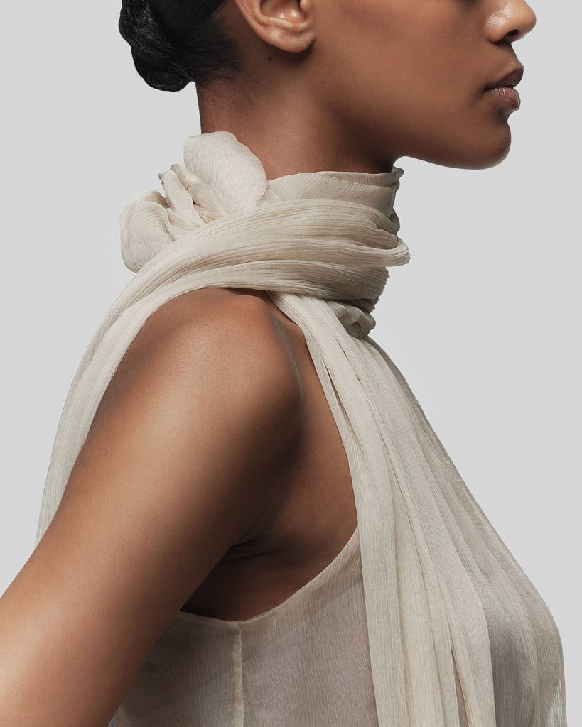 Woman wearing a light beige scarf with a neutral background