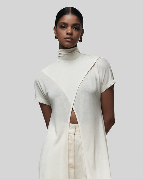 Woman wearing a white outfit with cut-out design on a plain background